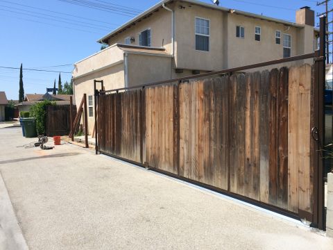 1968 Ford Mustang - A driveway with a tall wooden gate and metal frame, construction tools are nearby.