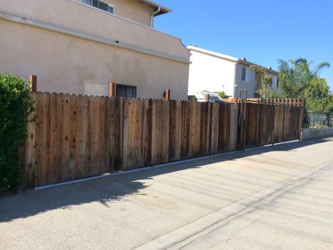 1968 Ford Mustang - A residential scene a tall wooden fence bordering a driveway and houses under a bright blue sky.