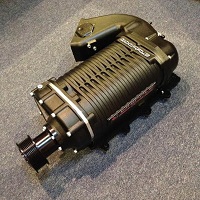 2004 Ford Crown Victoria - A black supercharger, likely a performance part, is shown from a close-up angle on a carpeted floor.