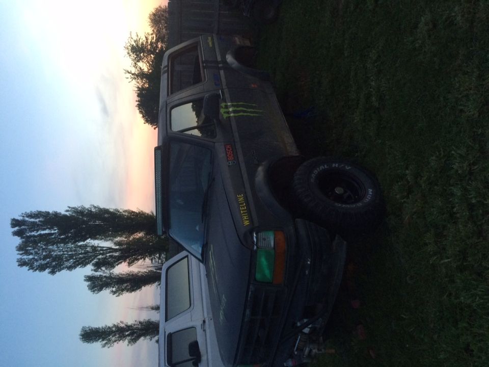 Dark Ford Bronco SUV with Monster claw decal and off-road tires parked on grass at sunset, photo rotated sideways