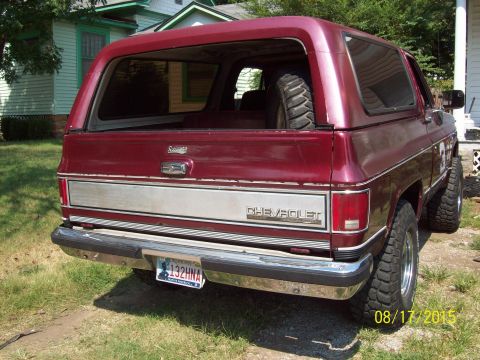1989 Chevrolet Blazer - The rear view of a red SUV shows a spare tire mounted inside and a Chevrolet badge on the tailgate.