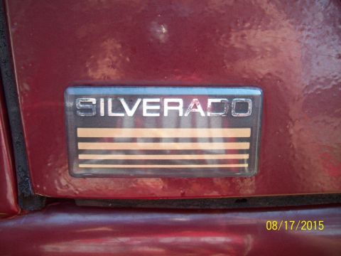 1989 Chevrolet Blazer - Close-up of a Silverado badge on a red vehicle, showing the model name and decorative stripes.