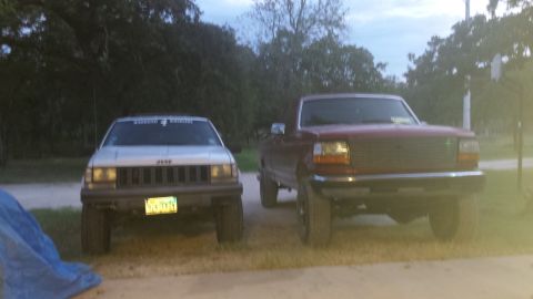 1994 Jeep Grand Cherokee - A silver Jeep Grand Cherokee is parked next to a red truck.