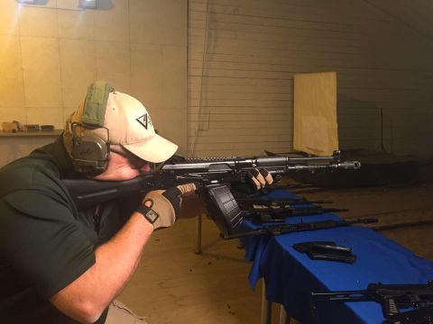 2000 Ford Crown Victoria - A person practices shooting a rifle at a range, with several other guns laid out on a table.