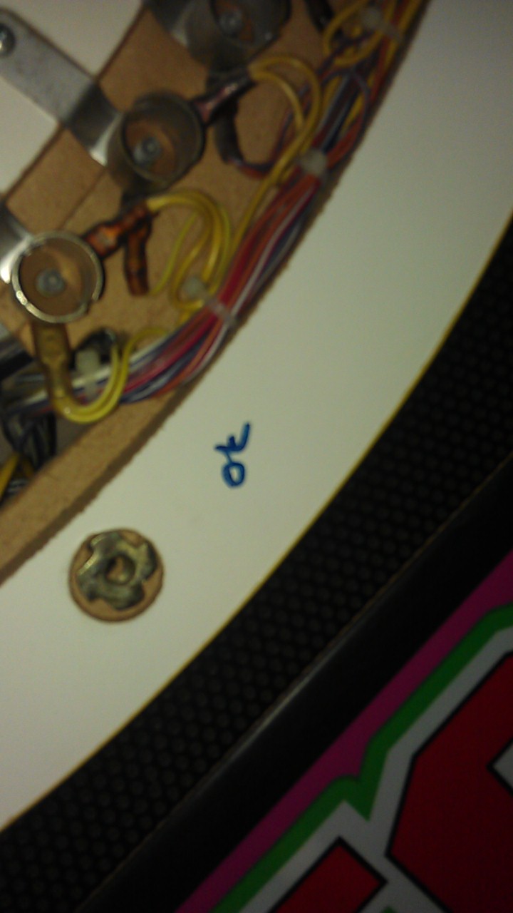 Close-up of wiring and metal components inside a machine, with blue ink writing that says 'ot'