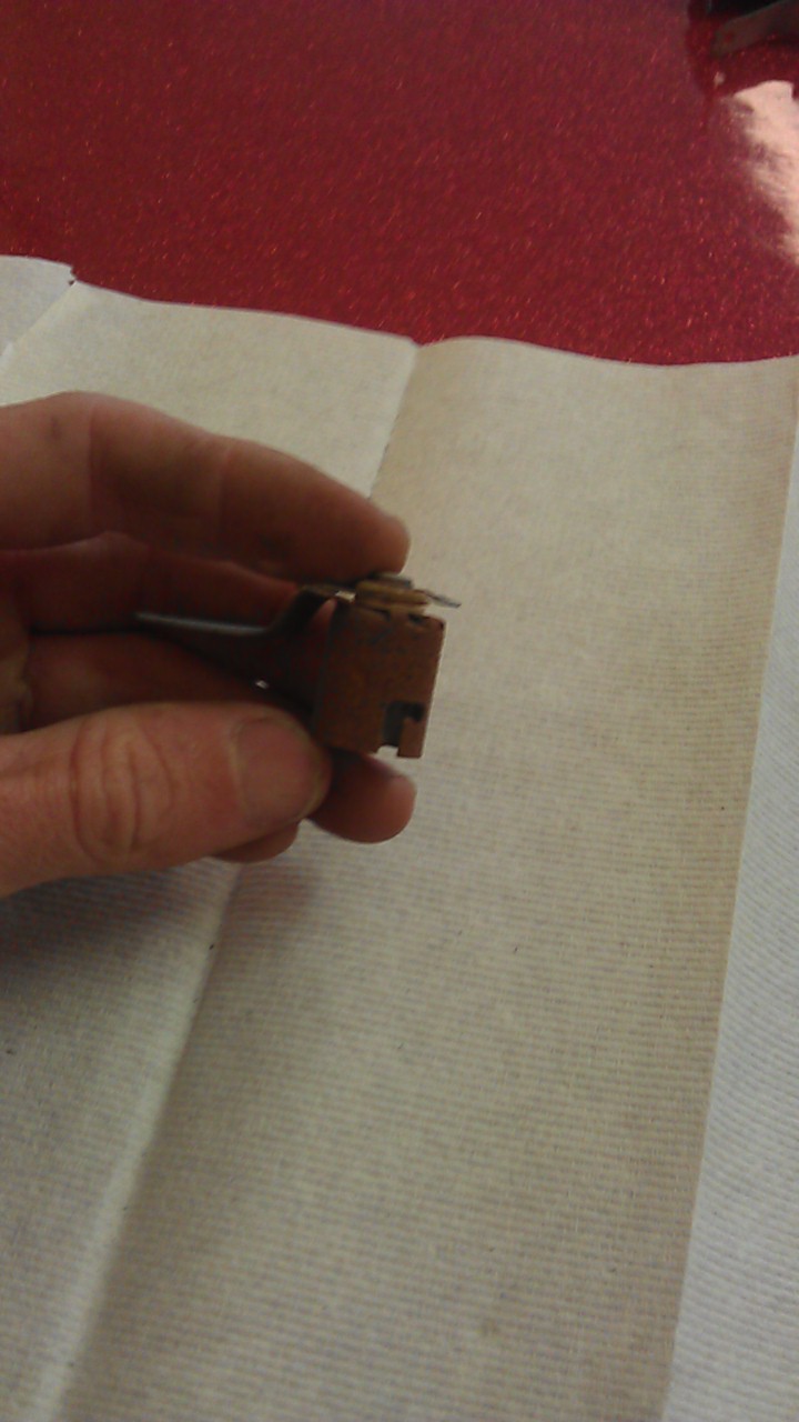 Hand holding a small, brown electrical component with metal contacts