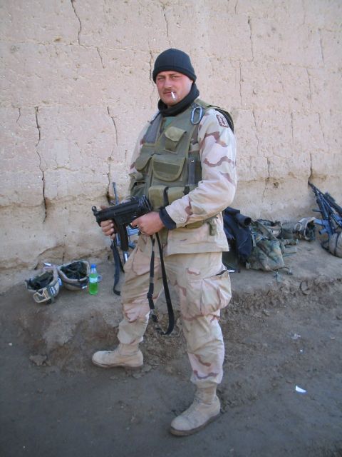 1981 Ford Bronco - A soldier stands with a firearm in a desert environment, wearing camouflage gear and a beanie.