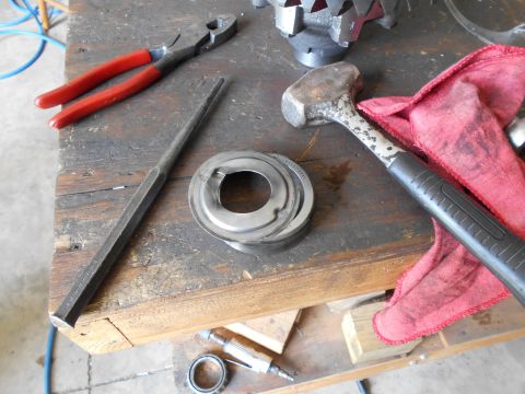 1992 Ford Bronco - Tools including pliers, a hammer, and a punch are laid out on a workbench next to a metal bearing race.