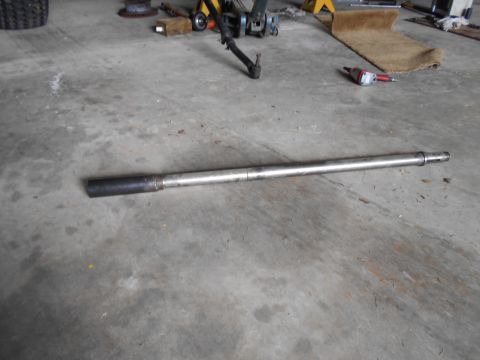 1992 Ford Bronco - A metal shaft, possibly a drive shaft or axle, rests on a garage floor with tools in the background.