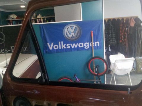 1982 Ford Bronco - Looking out from the driver's side of a vehicle at a Volkswagen banner and a unicycle.