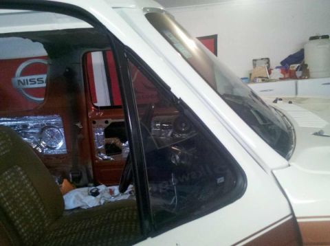 1982 Ford Bronco - Interior view of a vehicle undergoing repairs, showing soundproofing and a partial Nissan logo on the door.