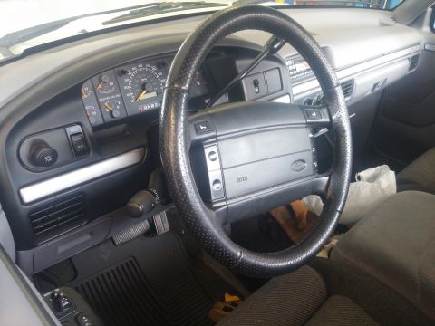 2000 Mercury Grand Marquis - The interior of a vehicle shows a dashboard with an instrument cluster and a black steering wheel.