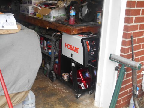 1994 Ford Bronco - A Hobart welder and cart are stored in a garage, with various supplies on shelves nearby.