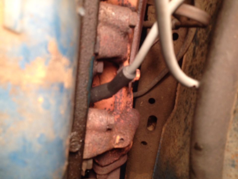 Rusty engine component with blue painted metal and a wire
