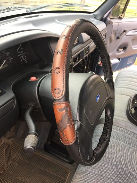 1993 Ford Bronco - Custom leather wrap on a Ford Bronco steering wheel shows 'BRONCO' lettering and a bull emblem.