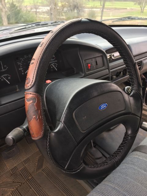 1993 Ford Bronco - Interior view of a 1993 Ford Bronco steering wheel with a custom leather cover and Ford emblem.