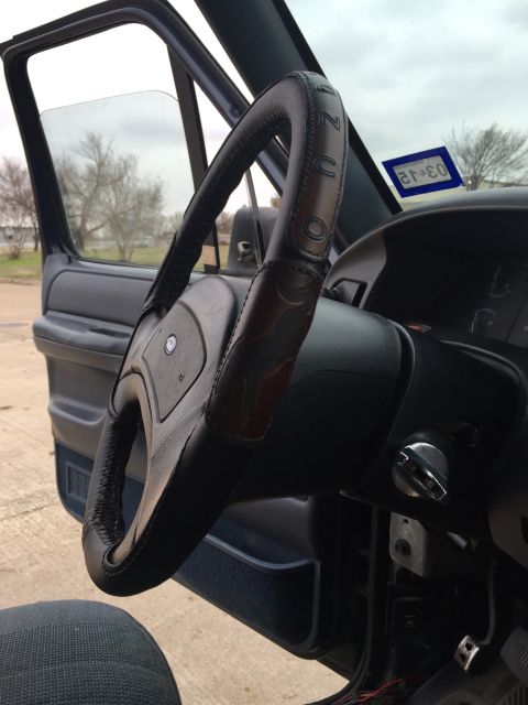 1993 Ford Bronco - Interior view of a 1993 Ford Bronco, a leather-wrapped steering wheel and a Texas inspection sticker on the windshield.