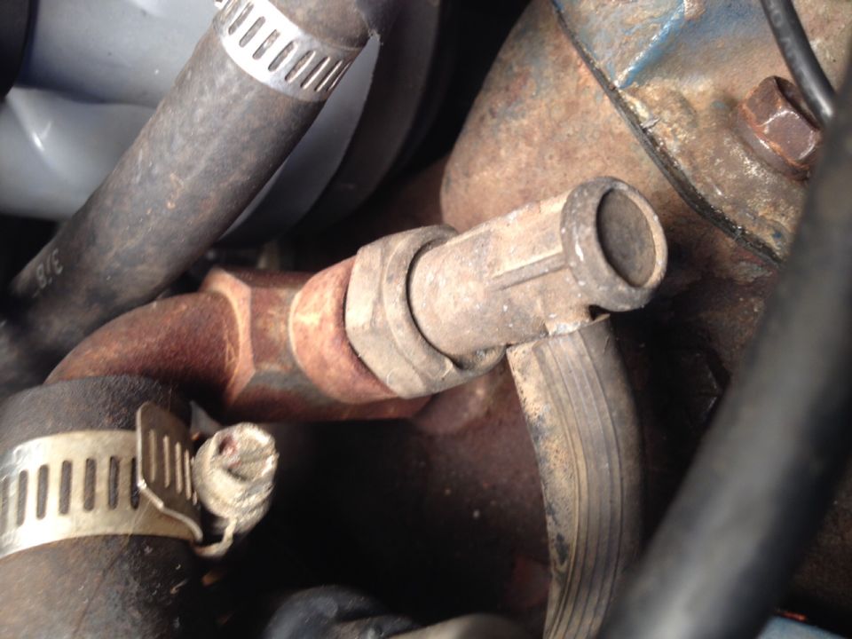 Close-up of a rusty engine hose fitting with a ribbed outlet.
