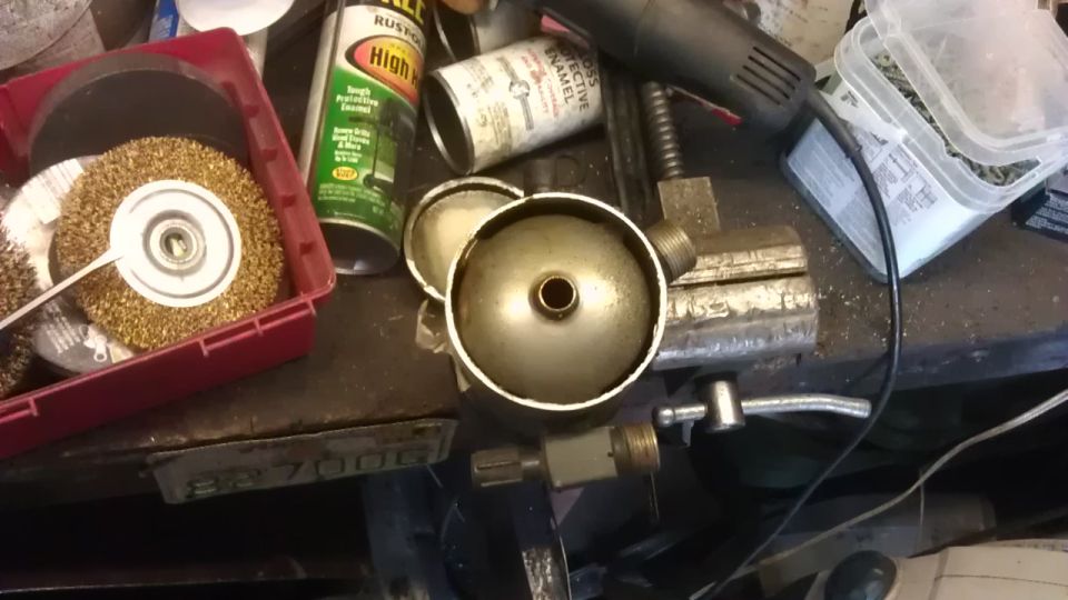 Workbench with tools, wire brushes, spray cans, metal canister, and vise.