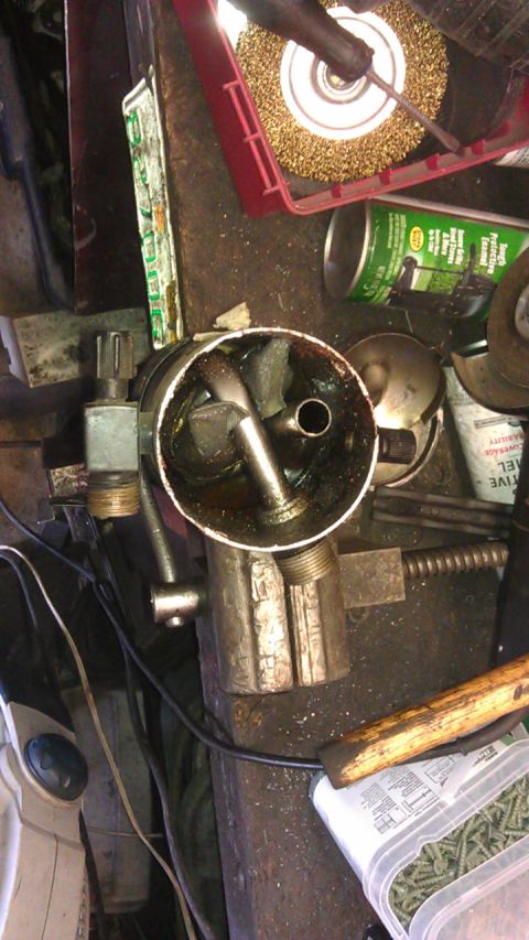 1994 Ford Bronco - This is a top-down view of a workbench with various tools and parts. A metal cylinder with internal components is prominent, surrounded by…