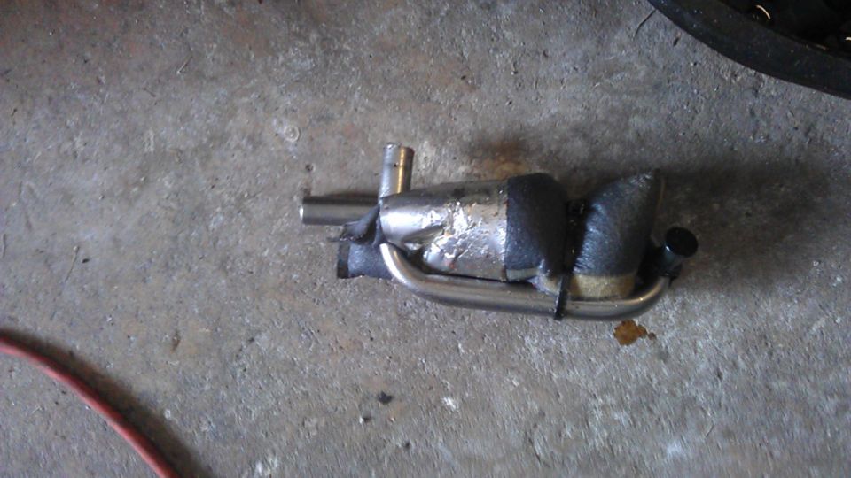 Custom exhaust part with stainless steel pipes and black wrap on concrete floor