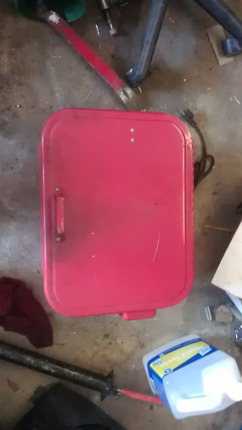 1994 Ford Bronco - A red metal box with a handle is on a concrete floor. There is a black cord plugged into the back of the box.