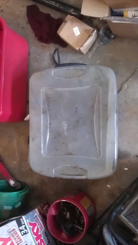 1994 Ford Bronco - A collection of items on a concrete floor, including a pink plastic container, a translucent plastic jug, a green bucket with a red-handled…