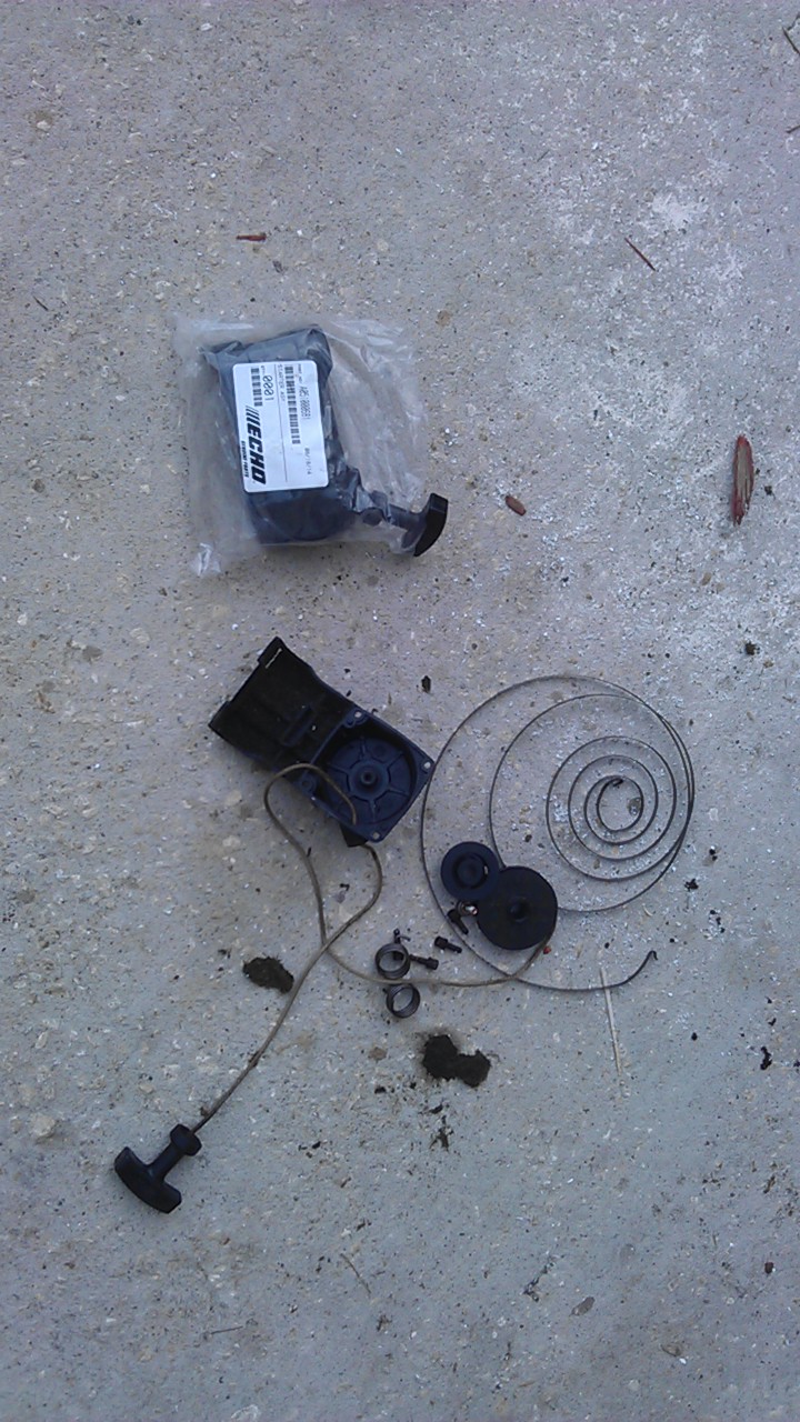 Disassembled ECHO recoil starter assembly on concrete.