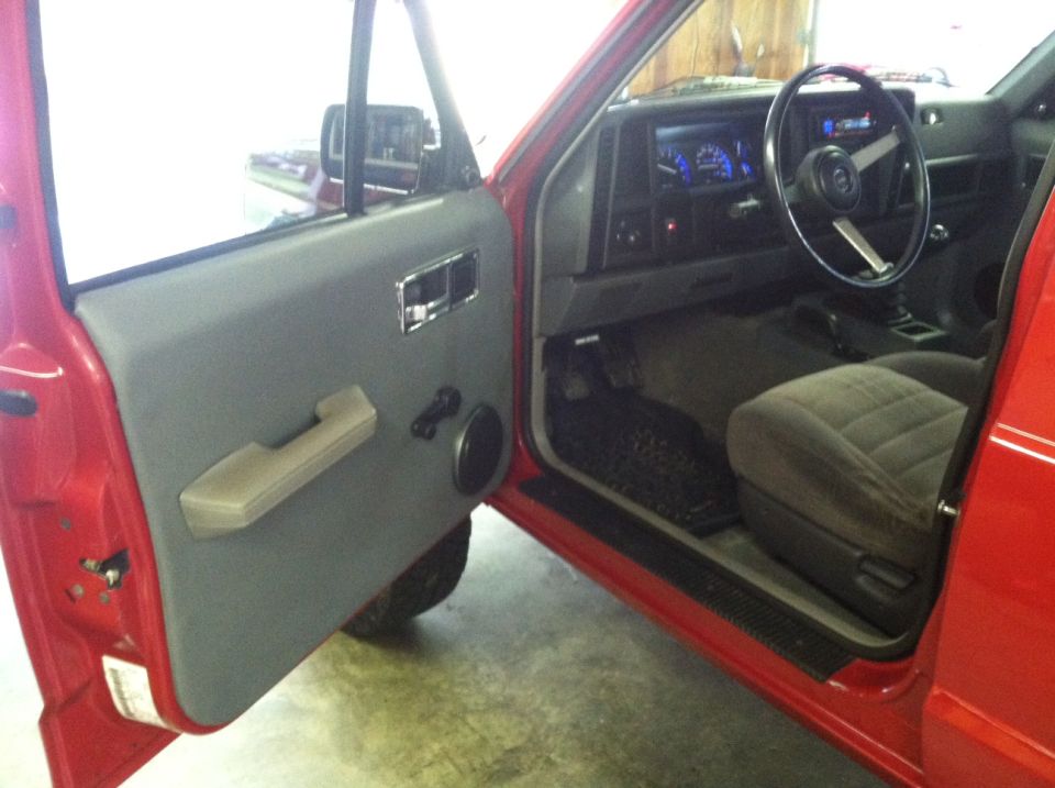 Interior of a red 1991 Jeep Comanche with driver's door open.