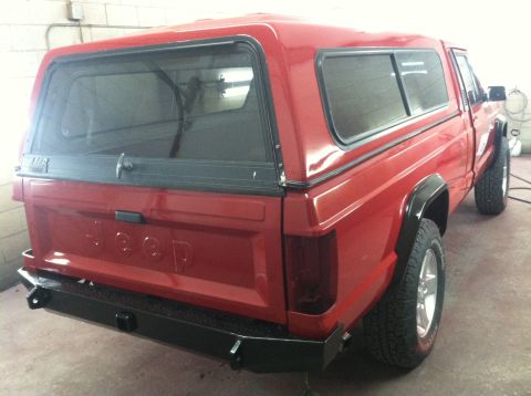 1991 Jeep Comanche - This red pickup truck is seen from the rear, parked indoors.