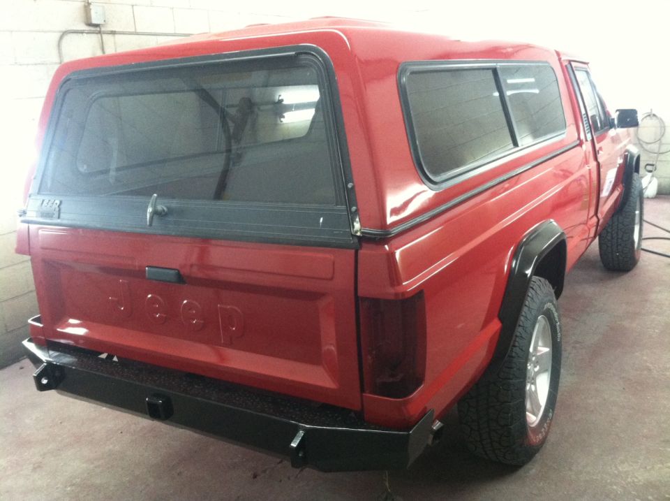 Rear view of a red pickup truck, possibly a Jeep Comanche
