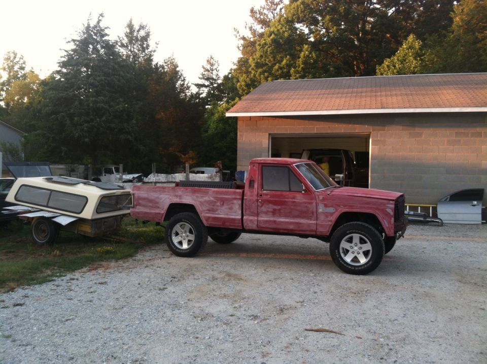 Red pickup truck side view, towing a camper shell on a trailer