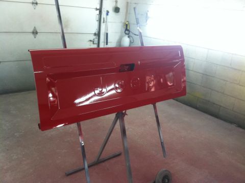 1991 Jeep Comanche - Newly painted red tailgate for a 1991 Jeep Comanche, mounted on a stand in a garage.