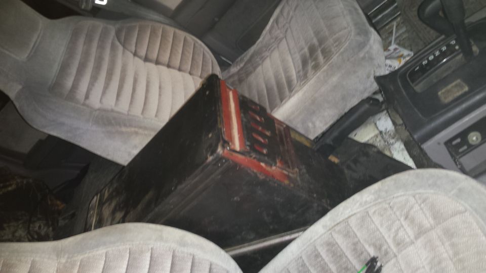 Interior of a vehicle showing front seats, center console, and a large black box.