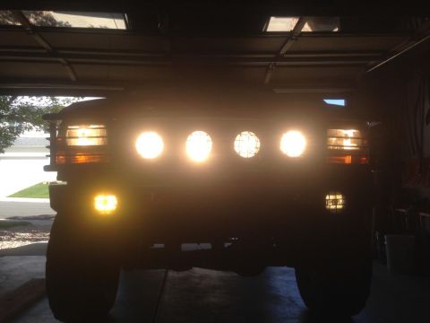 1996 Ford Bronco - The front of a dark-colored vehicle, likely a 1996 Ford Bronco, is illuminated by multiple bright lights, including headlights and auxiliar…