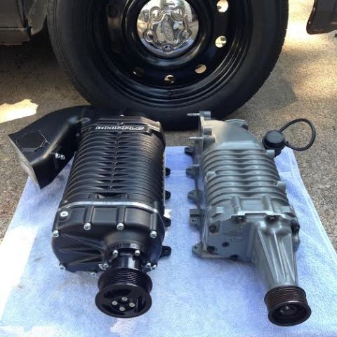 2004 Ford Crown Victoria - Two superchargers are shown side-by-side on a blue towel, with a black tire and chrome hubcap visible in the background.