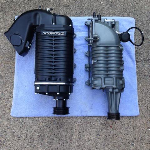2004 Ford Crown Victoria - Two superchargers are shown side-by-side on a blue towel. The supercharger on the left is black with a Whipple logo, and the one on the rig…
