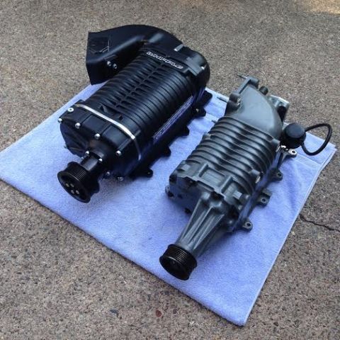 2004 Ford Crown Victoria - Two superchargers, one black and one gray, are placed on a light blue towel on a concrete surface. The black supercharger is larger and has…