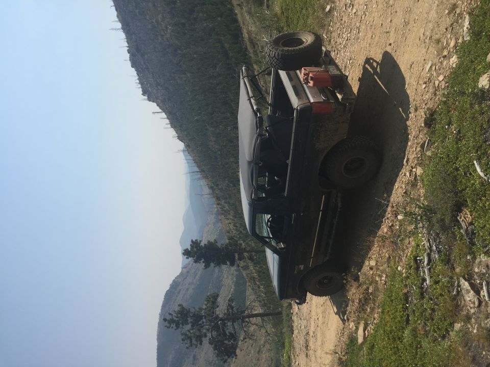1994 Ford Bronco parked on a dirt road on a mountainside.