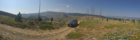 1994 Ford Bronco - 1994 Ford Bronco navigates a rough dirt track through a scenic, arid mountain terrain.