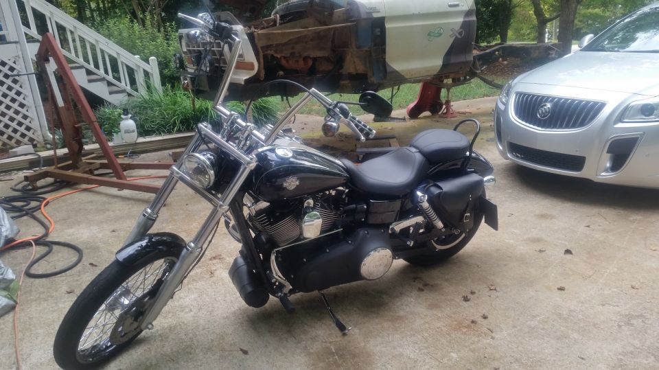 Black Harley-Davidson motorcycle parked outside next to a silver Buick