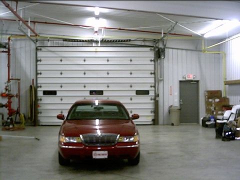 2000 Mercury Grand Marquis - A red sedan is parked inside a garage, facing a large white garage door.