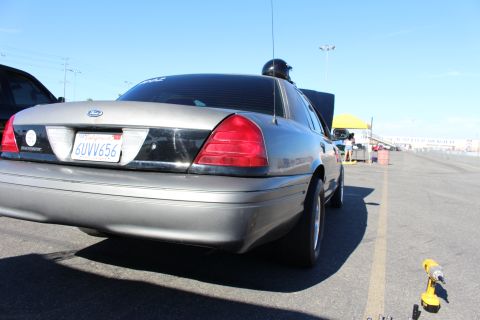 2003 Ford Crown Victoria - Rear three-quarter view of a gray Ford Crown Victoria with a California license plate parked along the staging lane at a dragway.