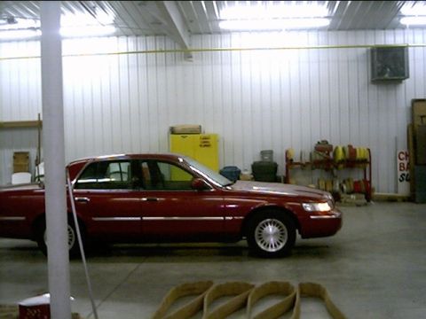 2000 Mercury Grand Marquis - Side view of a red 2000 Mercury Grand Marquis in an indoor setting.