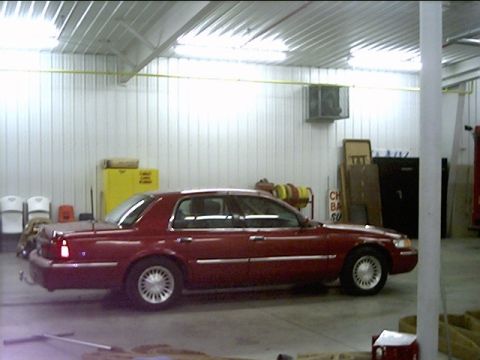 2000 Mercury Grand Marquis - A red sedan is parked indoors, with various items stored in the background.
