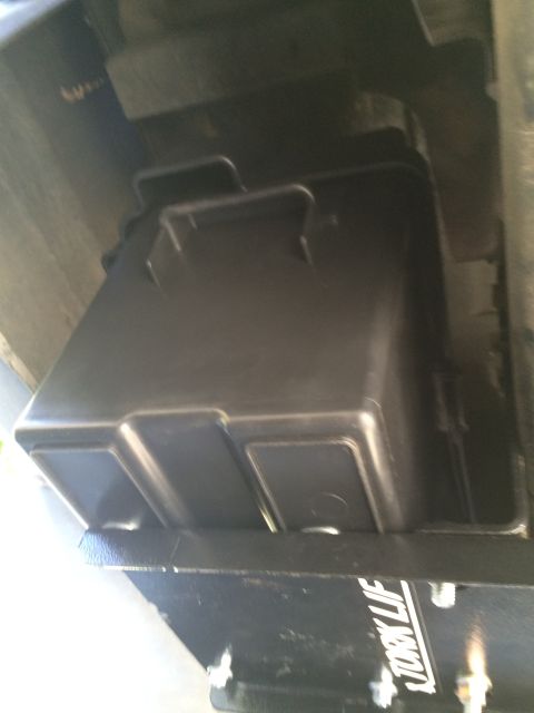 1997 Dodge 3500 - A black plastic storage box is mounted beneath a vehicle, with visible text on a bracket.