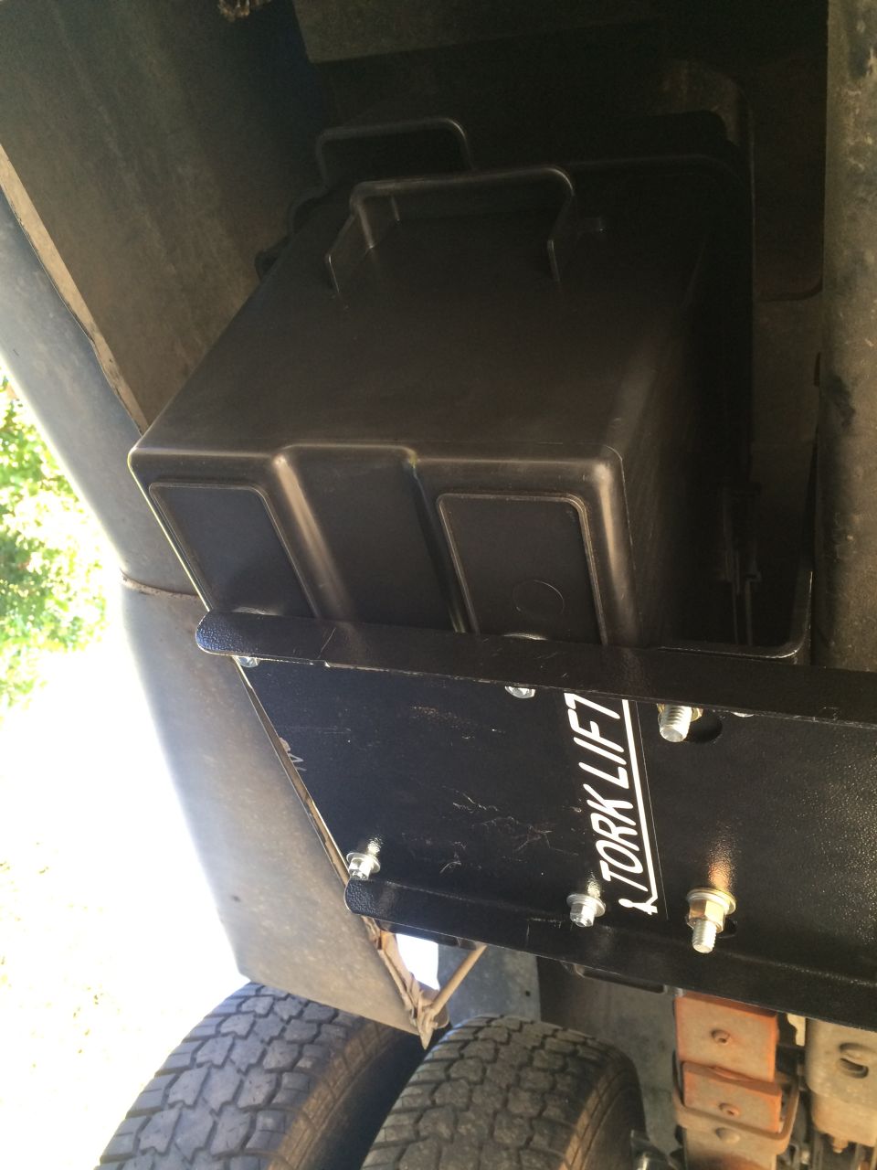 Black Tork Lift battery box mounted under a vehicle with dual rear wheels
