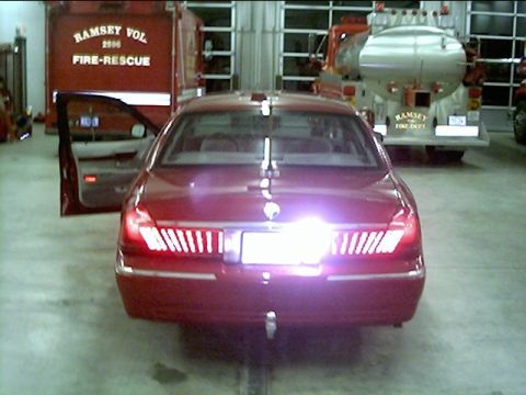 2000 Mercury Grand Marquis - A red sedan is parked in a fire station next to two fire trucks, one labeled Ramsey Vol Fire-Rescue.