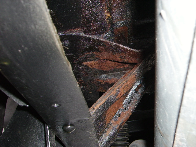 rusted frame components with black coating and some visible suspension parts