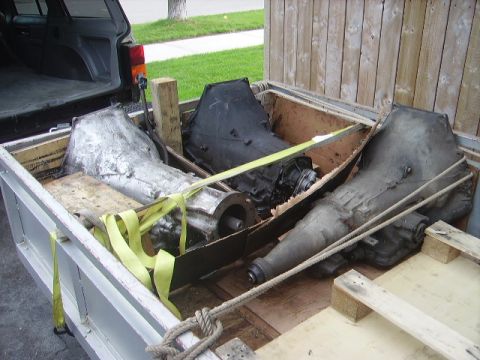 1978 Ford Bronco - Three transmissions are secured with straps and rope in the bed of a pickup truck.